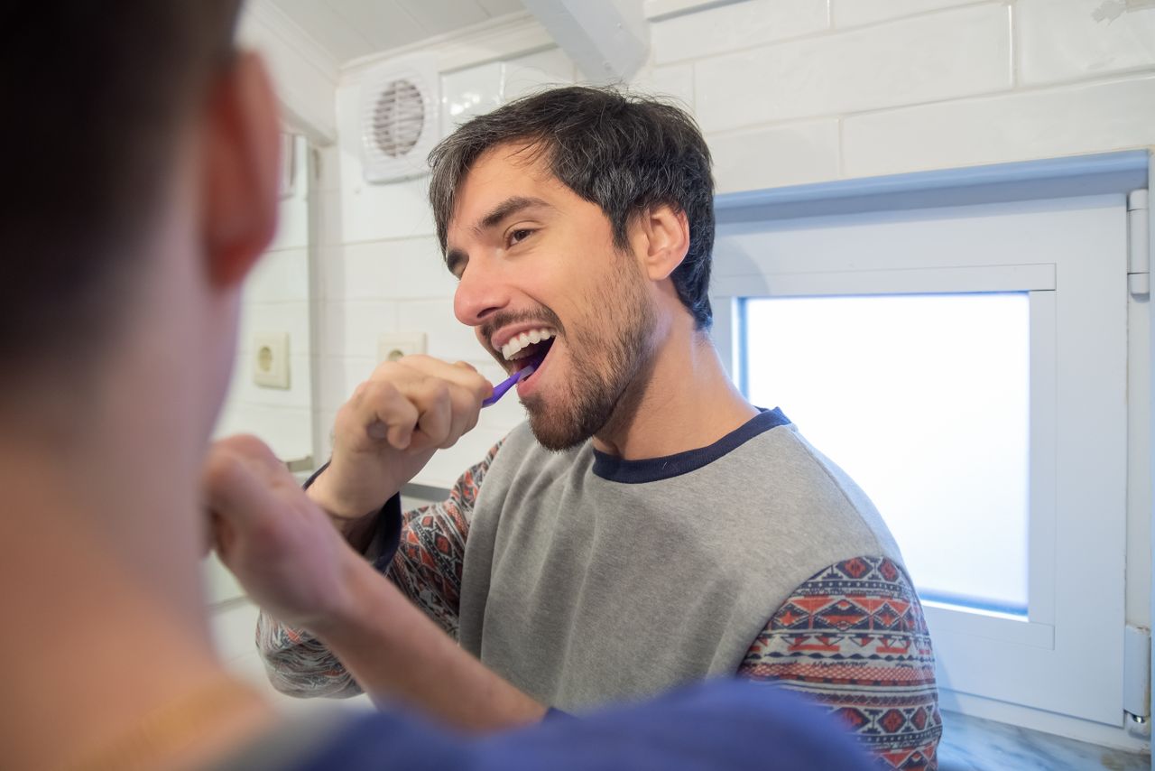 A loving couple shares a morning routine, brushing teeth together in a cozy bathroom.