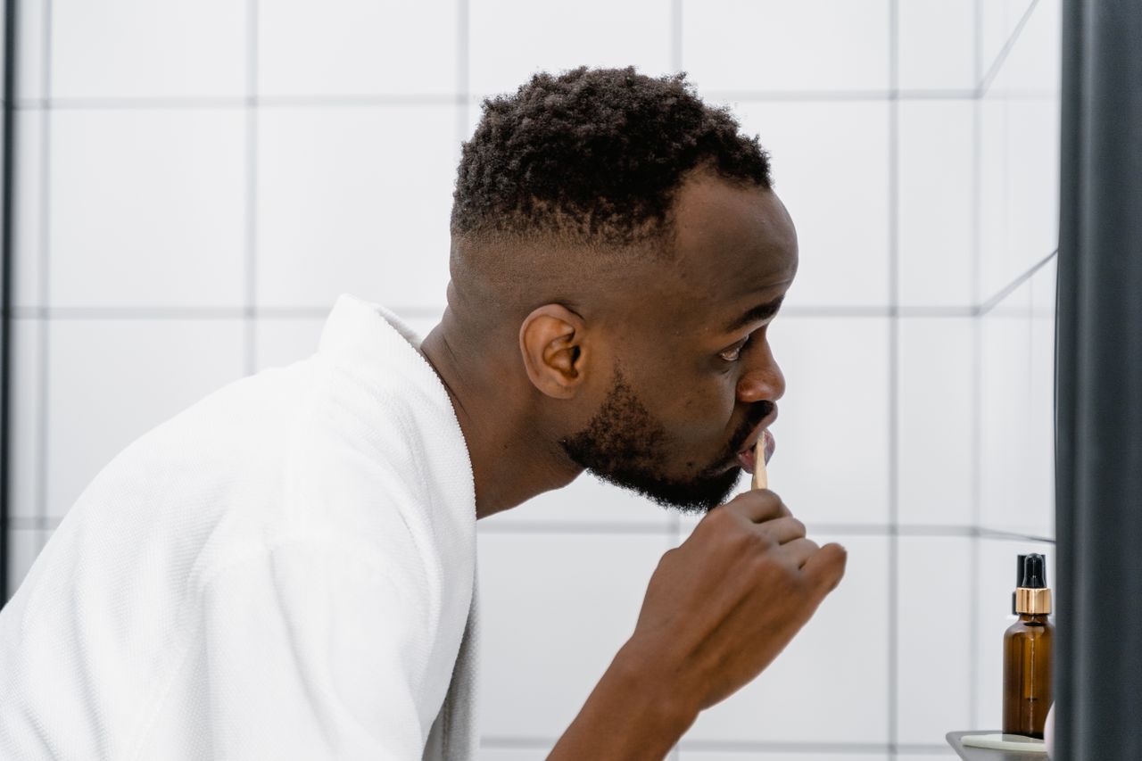 A man brushing his teeth in the bathroom, promoting good oral hygiene habits.